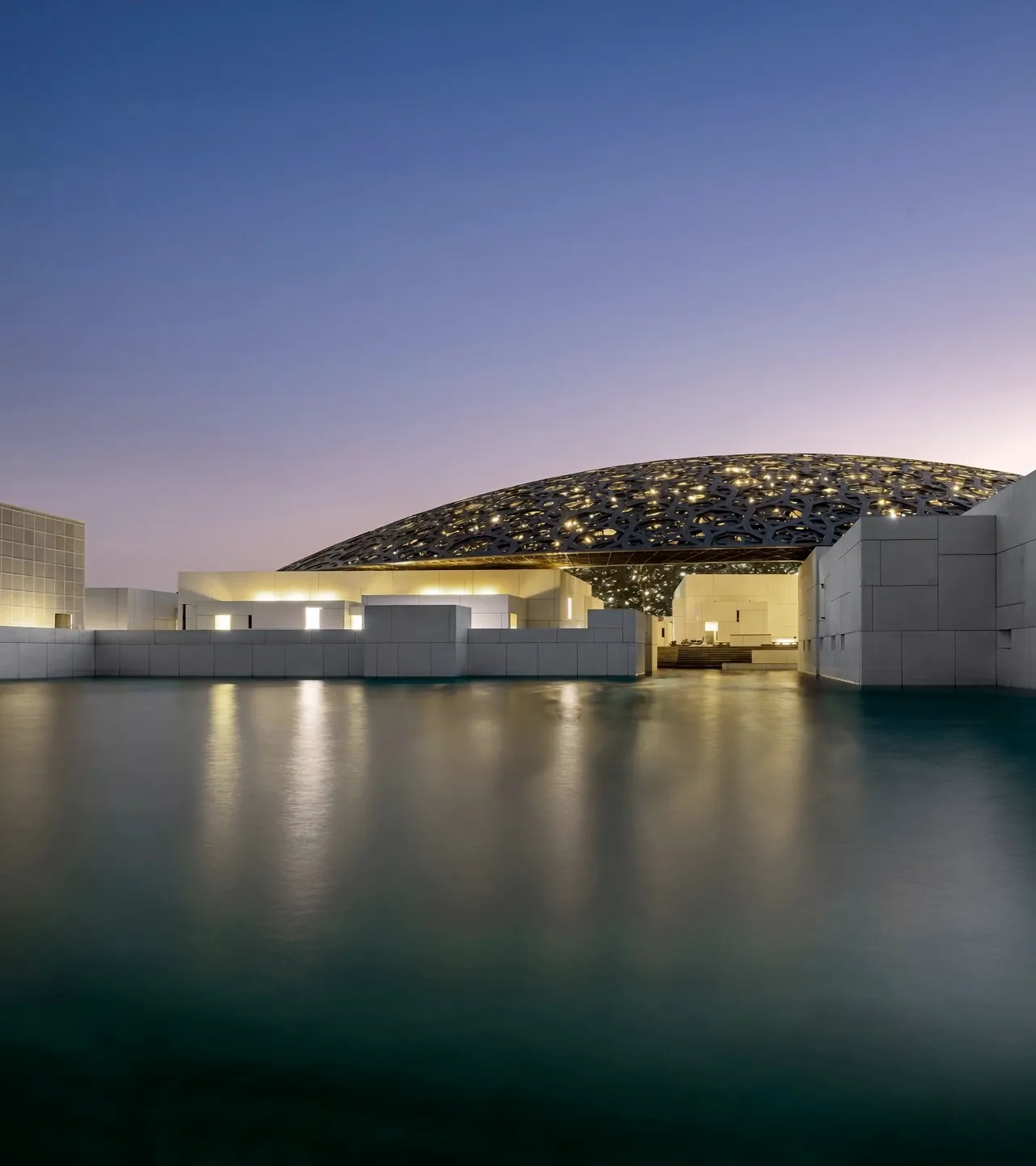 The Louvre Abu Dhabi dome at dusk over the water