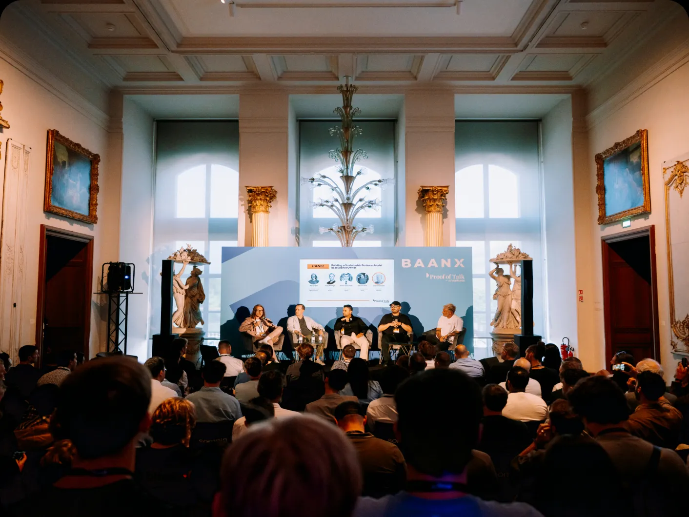 A packed panel session in a gilded salon at Proof of Talk
